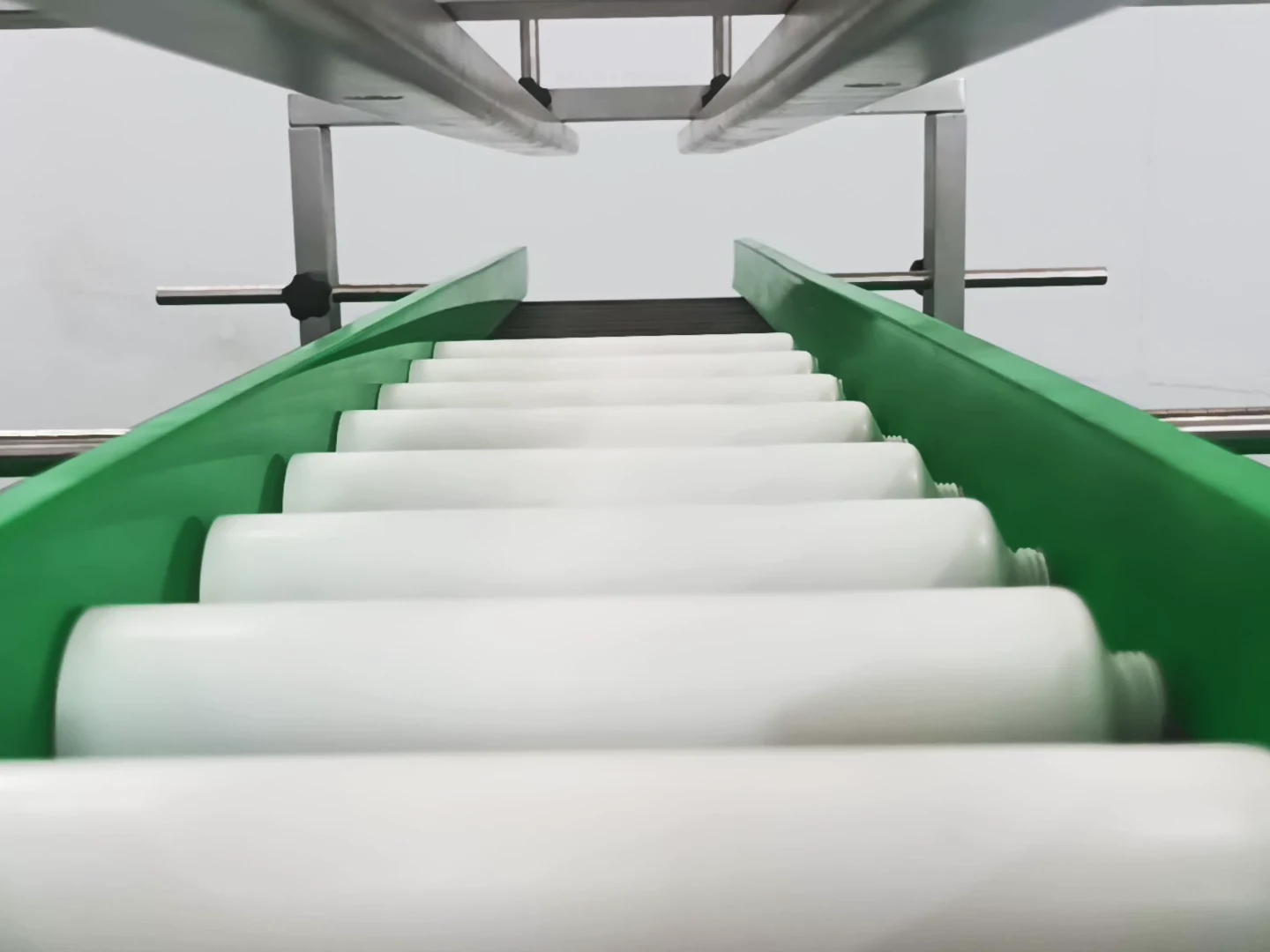 Product travelling between green guide rails on a KFlexiTrack flat belt conveyor