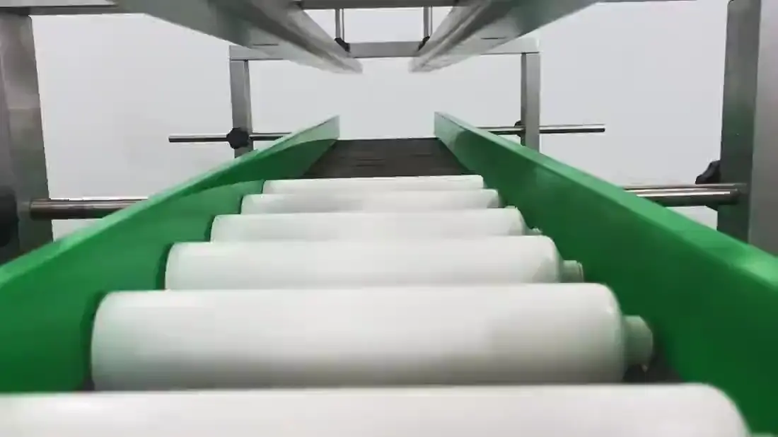 White tubes travelling on a green flat belt between guide rails